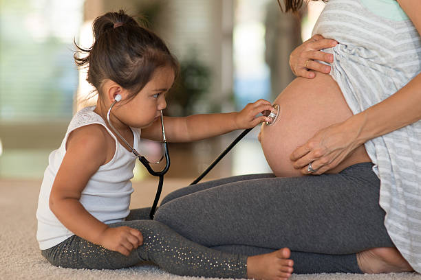 cute toddler listening to her pregnant mother's belly - mother exercising baby dieting imagens e fotografias de stock