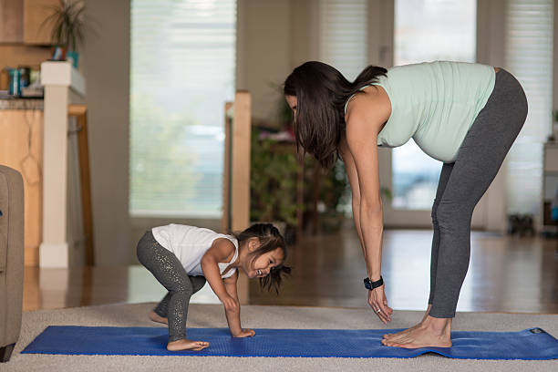 ethnic pregnant mother doing yoga with her young toddler - mother exercising baby dieting imagens e fotografias de stock