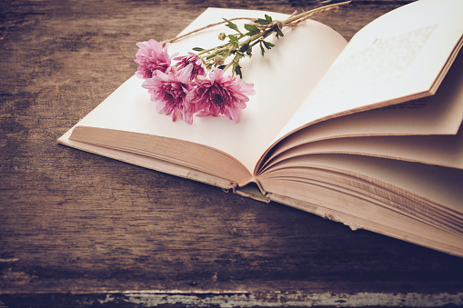 Vintage novel books with bouquet of flowers on old wood background - concept of nostalgic and remembrance in spring vintage background