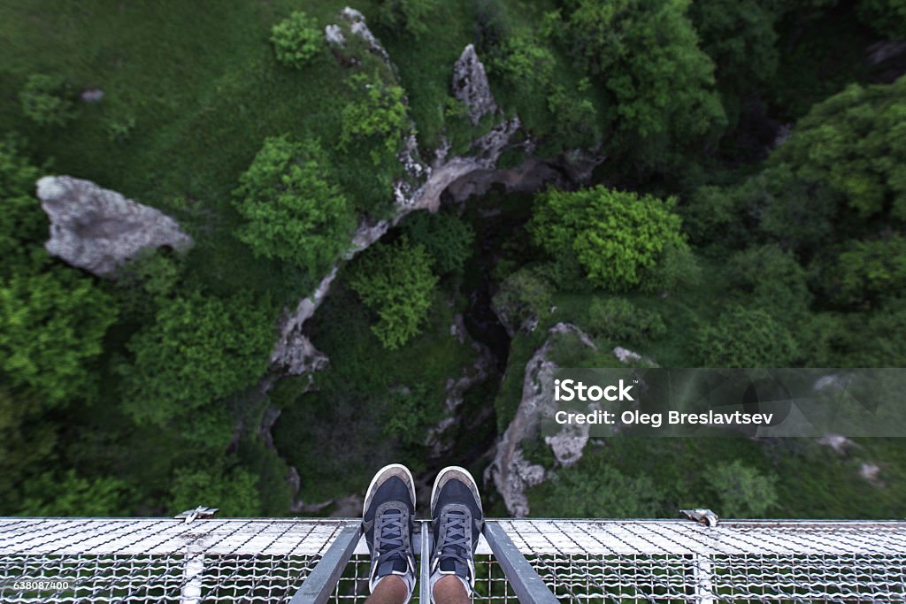 Man Feet standing on the edge of suspension bridge Man Feet standing on the edge of suspension bridge in Khndzoresk Cliff Stock Photo