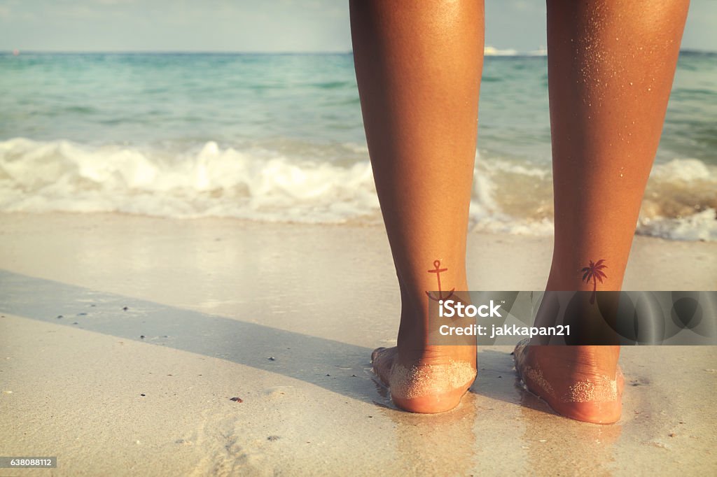summer beach Leisure in summer - Rear of beautiful women tan relax on beach with tattoo on foot. retro filter effect Tattoo Stock Photo