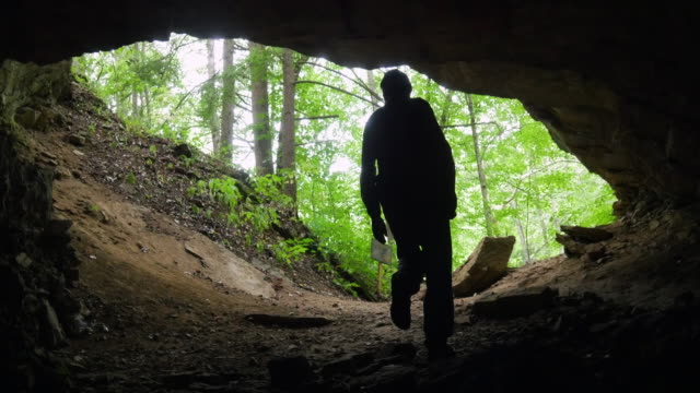 Caver Exits Dark Cavern into Lush Forest