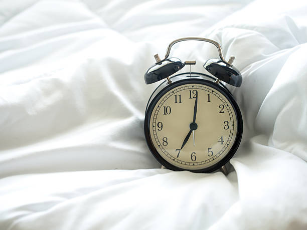 istock Alarm clock on bed in morning with sun light 638090454