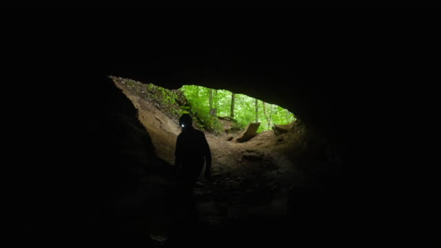 Spelunker Cautiously Enters a Limestone Cave