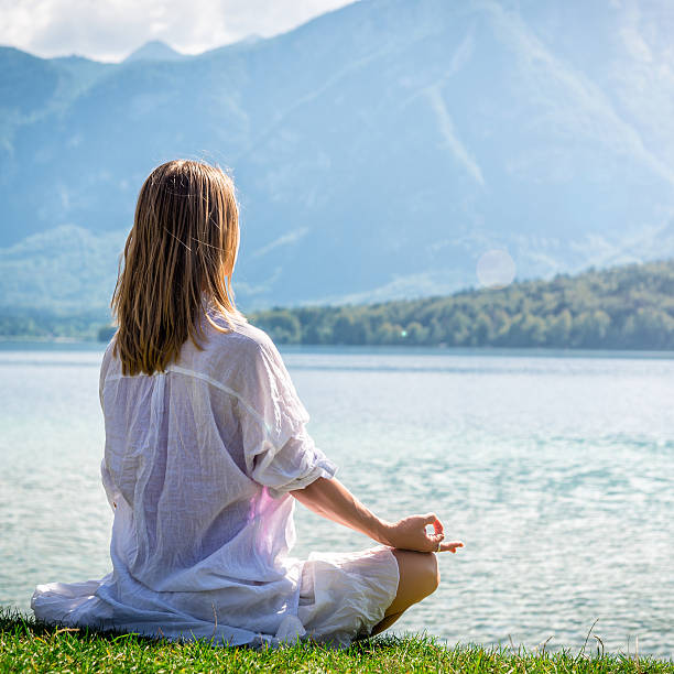 istock Woman meditating at the lake 638093308