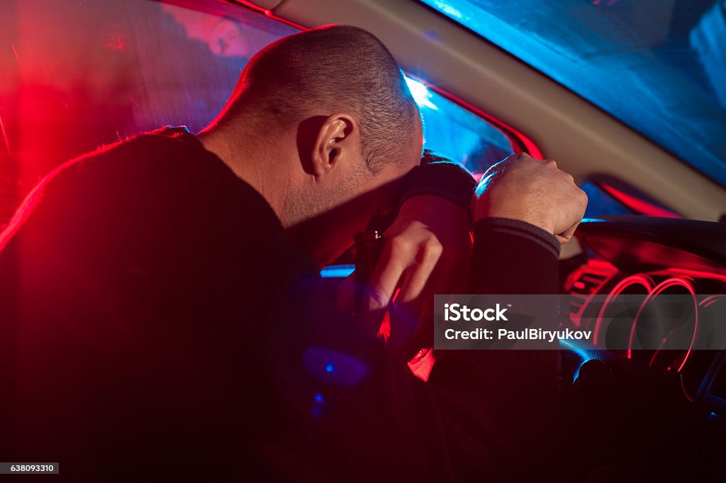 Hombre borracho que cubre su cara de la luz del coche de policía - Foto de stock de Cuerpo de policía libre de derechos