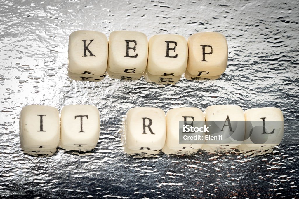 Keep it real text Keep it real text on a wooden cubes on a shiny silver background Advice Stock Photo