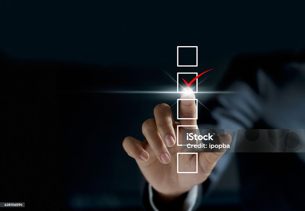 businessman checking mark on checklist with a red marker businessman checking mark on checklist with a red marker on dark background Choice Stock Photo