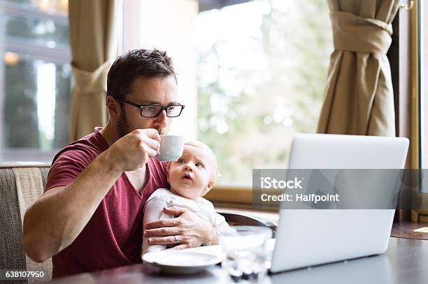 Man With Notebook In Cafe Drinking Coffee Holding His Son Stock Photo - Download Image Now