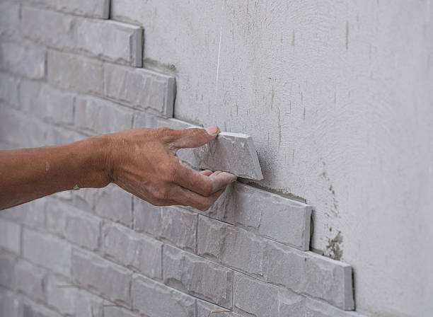 istock worker install stone wall tile with cement for house 638108030