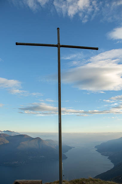 Religious Cross on mountain peak above the beautiful view of lake Maggiore and the European Alps.