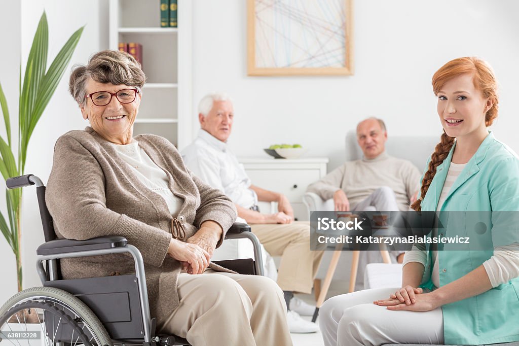 Senior on a wheelchair Senior on a wheelchair with young nurse Nursing Home Stock Photo