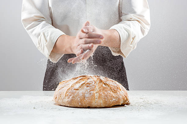 The male hands in flour and rustic organic loaf of The hands of baker man and rustic organic loaf of bread - rural bakery on gray baking bread stock pictures, royalty-free photos & images