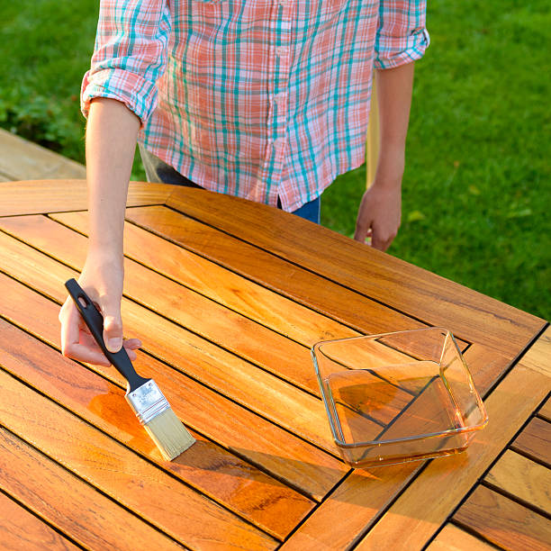 istock hand holding a brush applying varnish on a garden table 638116398