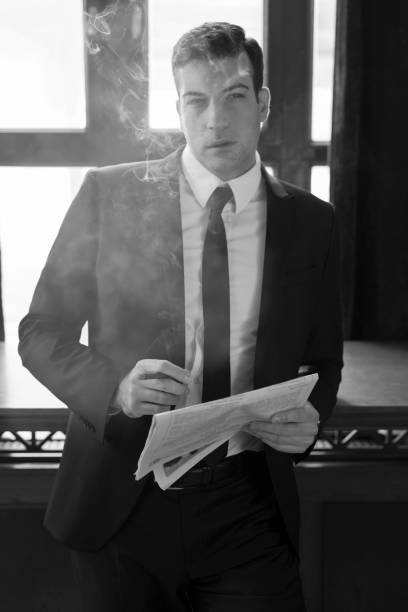 No woman can't resist me Young handsome businessman standing and leaning leisurely on the table at the cafe, holding newspapers and smoking a cigar smoking women luxury cigar stock pictures, royalty-free photos & images