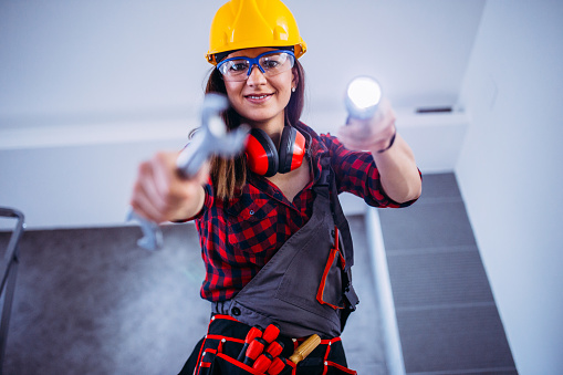 Female construction worker with tools.Female takes care of the house.Woman handyman.There helmet on his head and a tool belt on