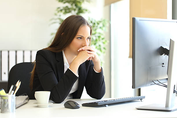 Businesswoman solving a difficult assignment Concentrated businesswoman trying to solve a difficult assignment on line in a desktop computer at office suspicion stock pictures, royalty-free photos & images