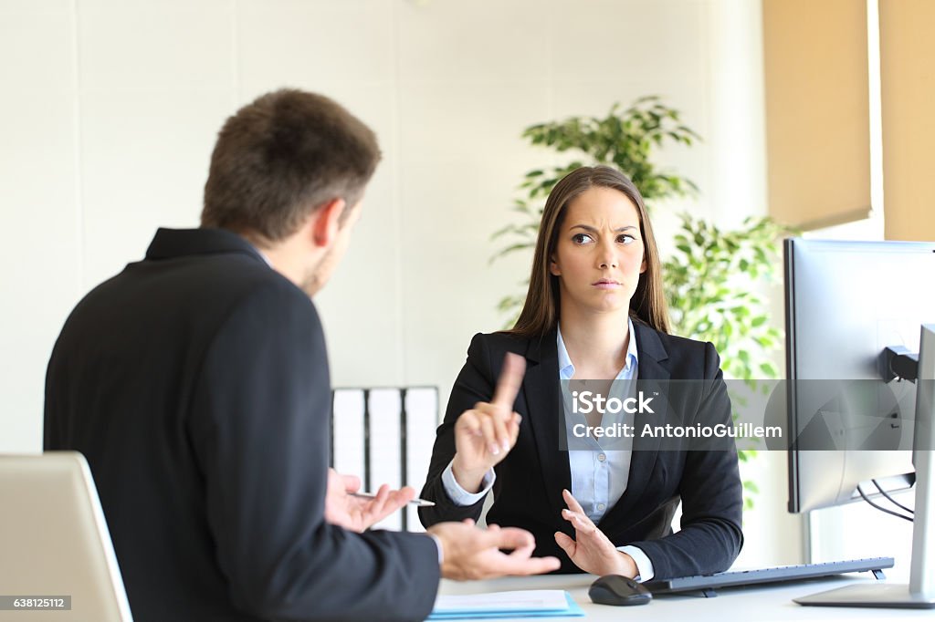 Boss denying something to an employee Boss denying something saying no with a finger gesture to an upset employee in her office Rudeness Stock Photo