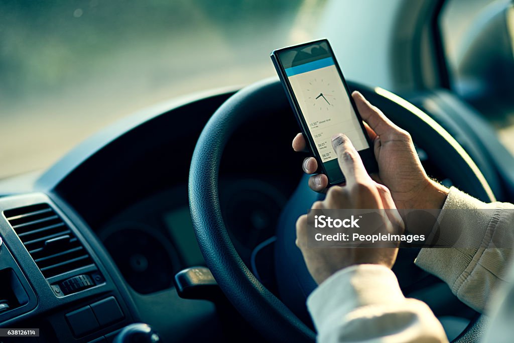 Staying on schedule Closeup shot of an unidentifiable delivery man using a cellphone while sitting in his van Truck Driver Stock Photo