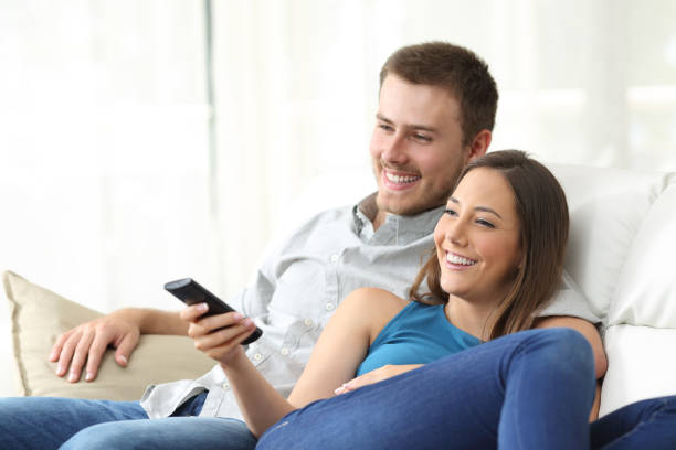 istock Happy couple watching tv at home 638126662