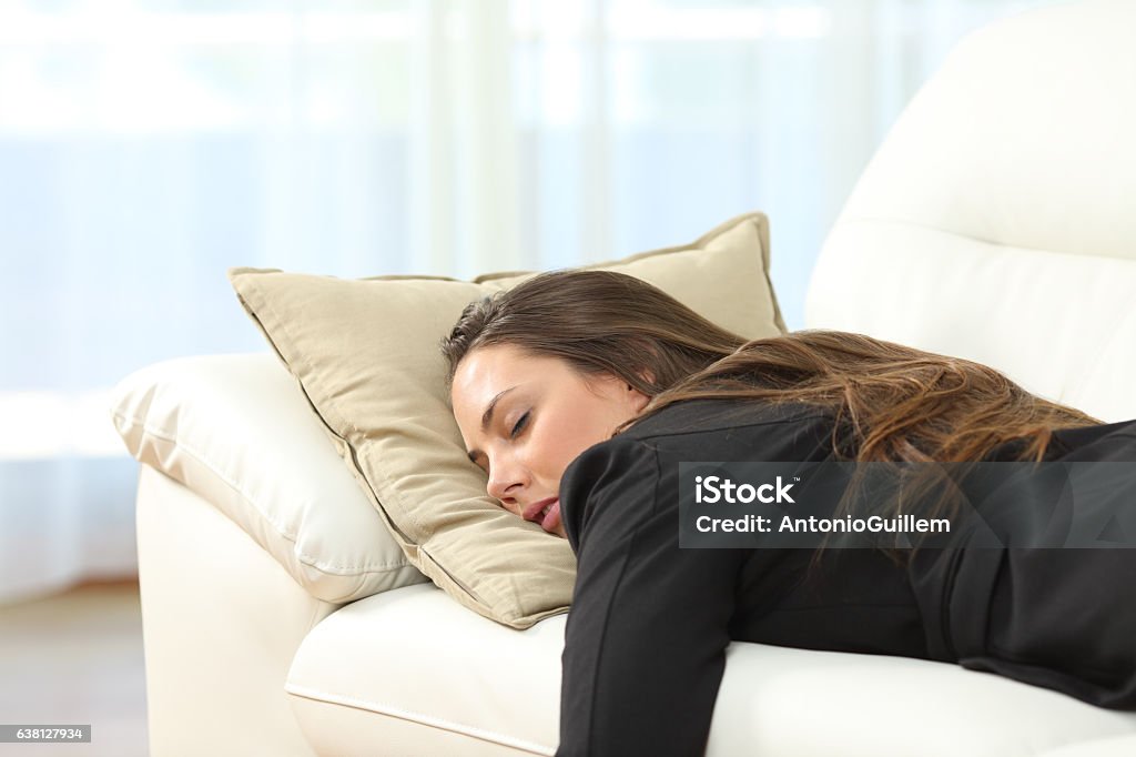 Tired executive sleeping at home after work Tired executive sleeping lying on a sofa in the living room at home after work Sleeping Stock Photo