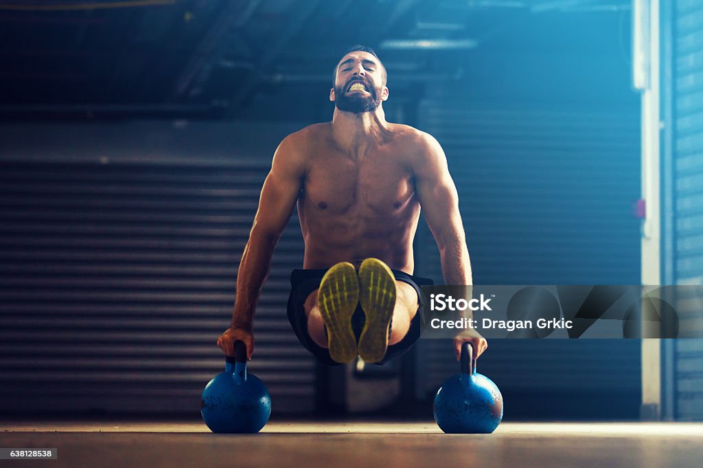 Young strong man Young fitness man is training by kettlebell. Human Face Stock Photo