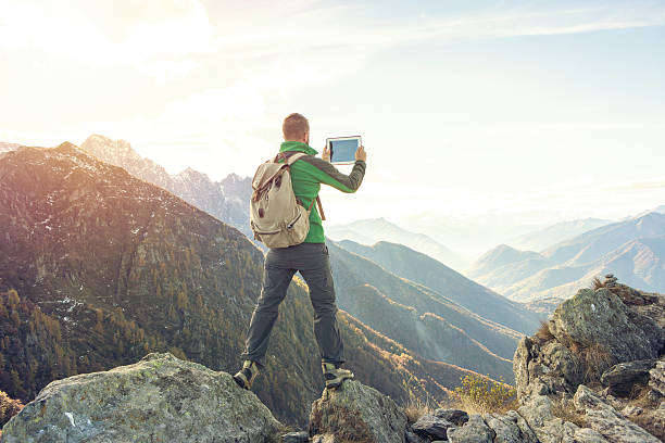 istock Young man takes digital tablet picture on mountain top 638130946