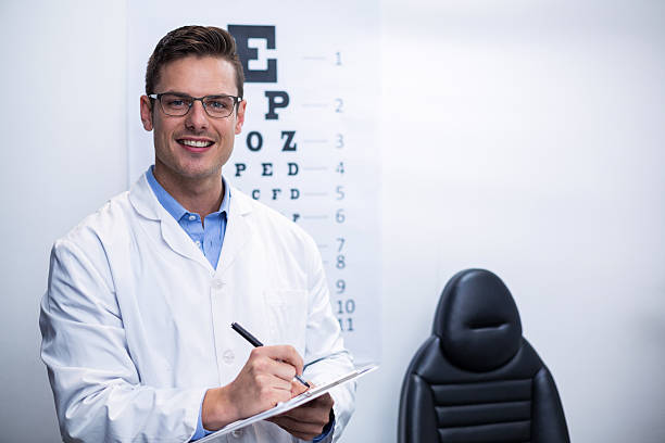 optometrist schreiben auf zwischenablage - optometrie stock-fotos und bilder