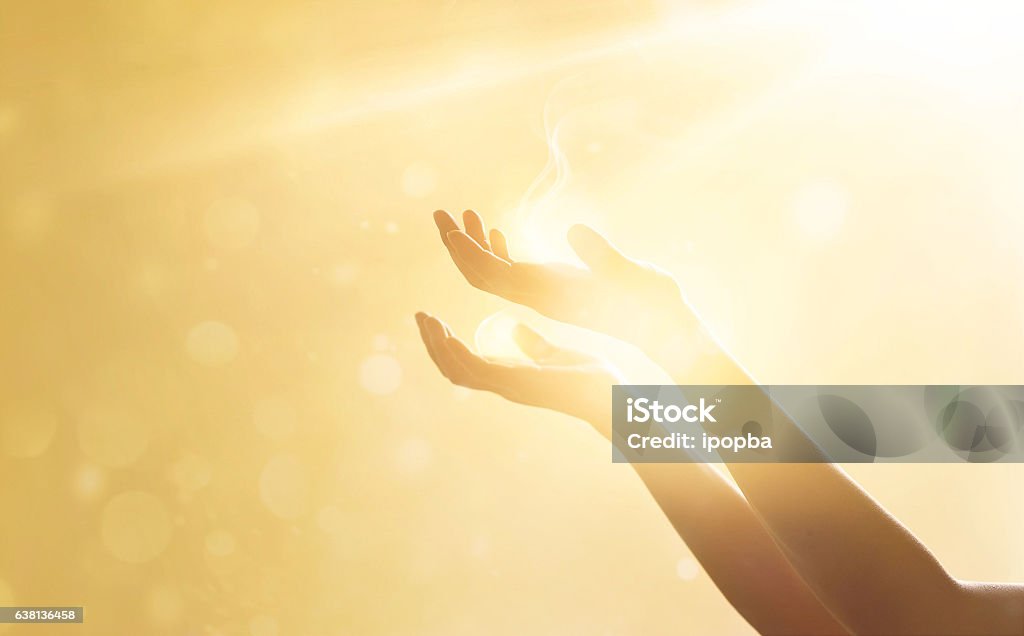 Woman hand praying for blessing from god on sunset background Spirituality Stock Photo