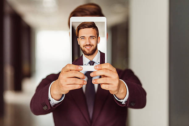 Businessman showing selfie on tablet Smiling man showing photo on tablet pc obscured face photos stock pictures, royalty-free photos & images
