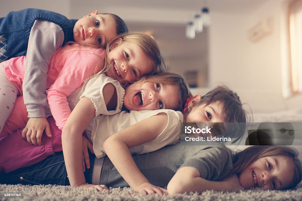 Children having fun at home. Large group of children lying at floor and having fun. Looking at camera. Brother Stock Photo