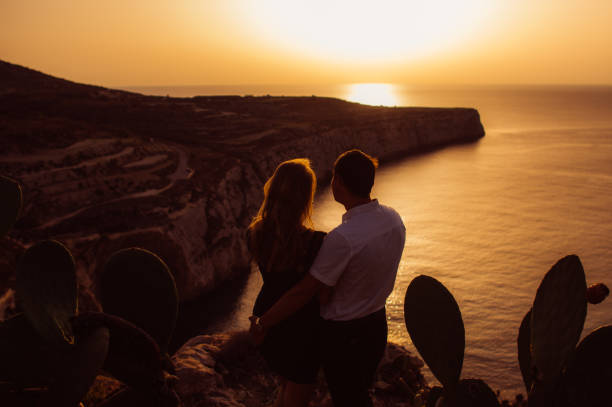 Couple in the evening on the seaside Couple in the evening on the seaside looks to the sun maltese silhouette stock pictures, royalty-free photos & images