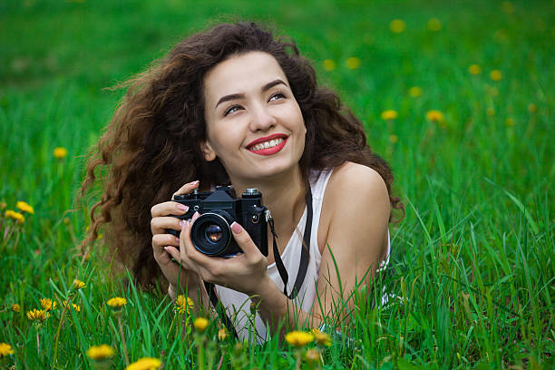 istock Beautiful girl holds camera and lying on the grass. 638157598