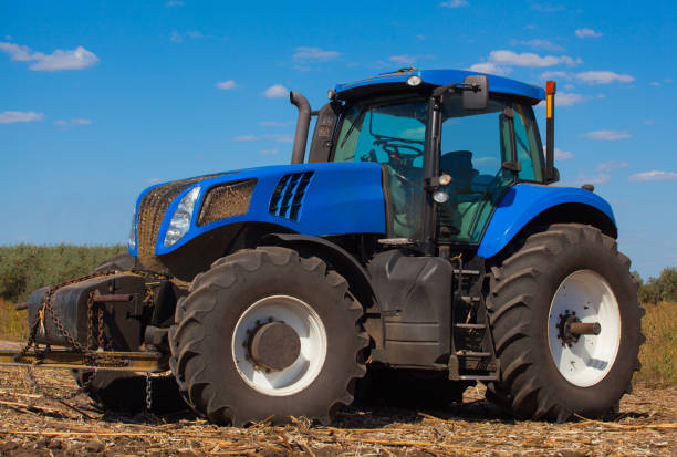 istock Large, new blue tractor plowing a field after harvest. 638160030