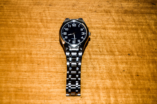 Detail of a wristwatch on top of a wooden desk.