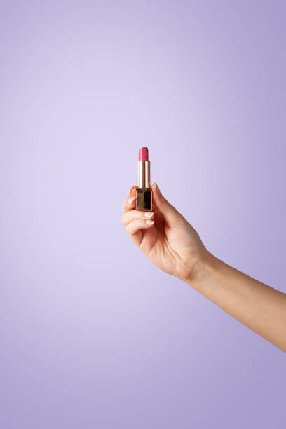 istock Woman hand holding a lipstick on violet background 638163616