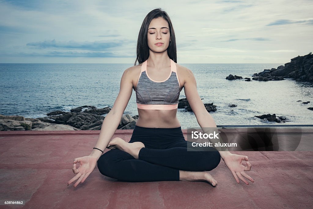 Woman doing yoga exercises at the sea Young woman doing yoga at the sea 20-29 Years Stock Photo