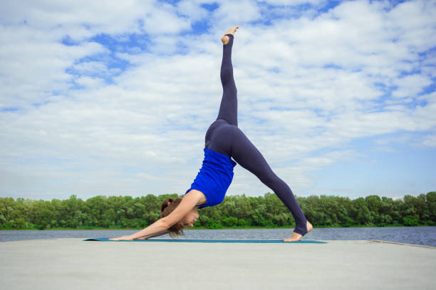 Woman performs yoga move on snow summit, sky background
