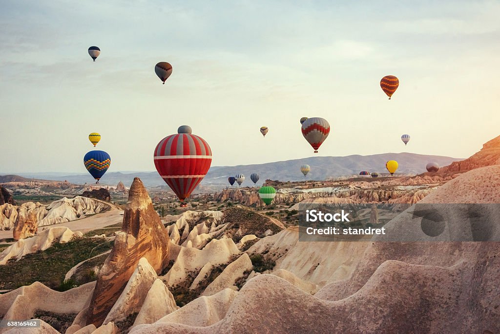 Hot air balloon flying over rock landscape at Cappadocia Turkey. Hot air balloon flying over rock landscape at Cappadocia Turkey. Cappadocia with its valley, ravine, hills, located between the volcanic mountains in Goreme National Park. Cappadocia Stock Photo