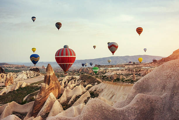 Hot air balloon flying over rock landscape at Cappadocia Turkey. Hot air balloon flying over rock landscape at Cappadocia Turkey. Cappadocia with its valley, ravine, hills, located between the volcanic mountains in Goreme National Park. rock hoodoo stock pictures, royalty-free photos & images
