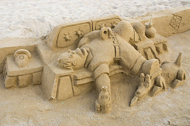 Sand sculpture of a bear with tattoo and hat looking annoyed while rowing a boat. This sand sculpture is made by Bouke Atema and photograped by Bouke Atema.