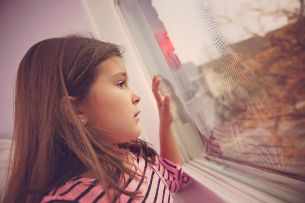 istock Sad little girl looking through a window 638170002