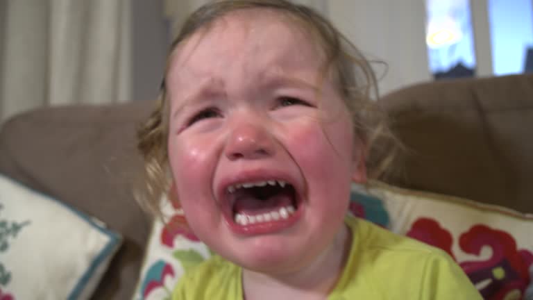 Toddler girl crying with mouth wide open and tears down her face