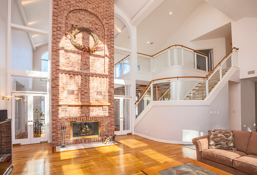 Amazing home interior architecture, cathedral ceiling with brick fireplace and spectacular glass staircase.