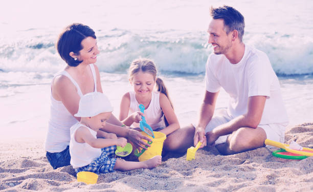 istock Parents with two kids playing with toys on beach 638178896