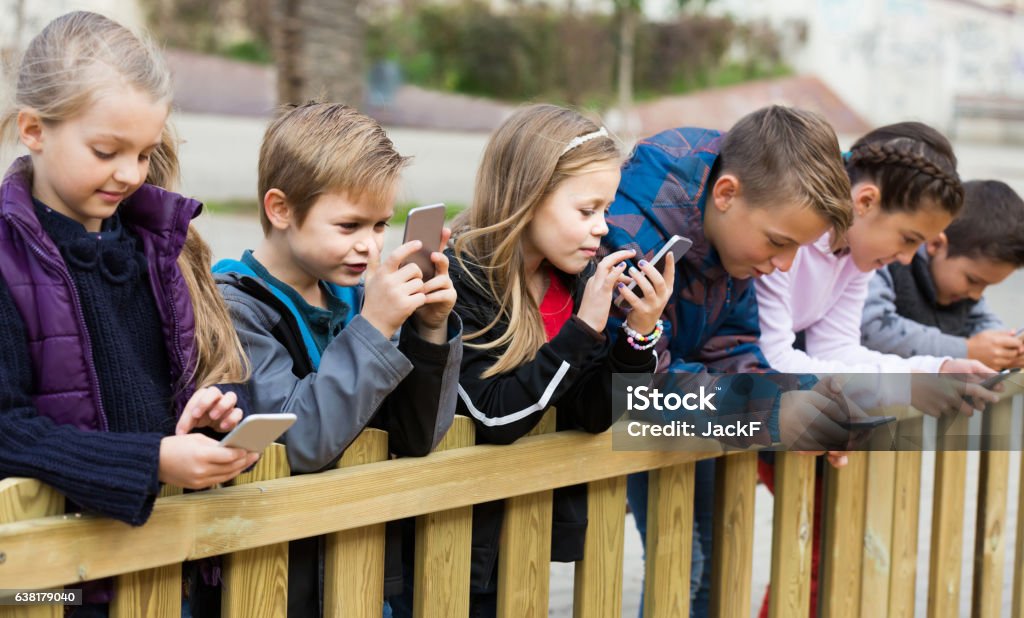 Outdoor-Porträt von Mädchen und Jungen spielen mit Handys - Lizenzfrei Kindheit Stock-Foto