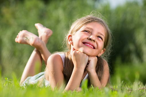 An 8 year old girl with blond hair is laughing in a country field. Photo taken on Lemnos island in Greece.