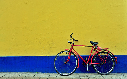 Red bicycle parking in front of the yellow and blue wall