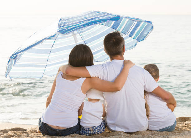 istock back view on family of four sitting on beach 638189552