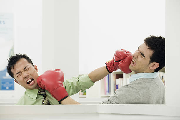 par de colegas de escritório lutando com luvas de boxe no escritório - boxing caucasian men business - fotografias e filmes do acervo